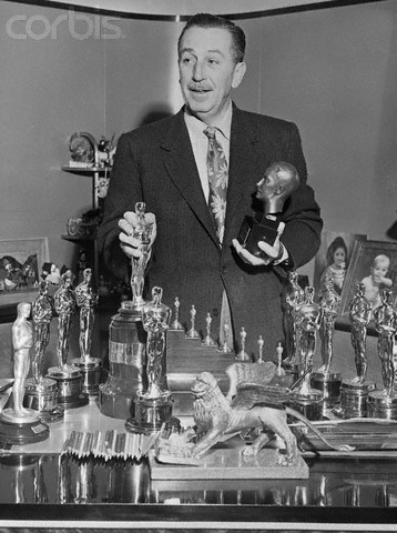 Walt Disney Standing over Table of Trophies